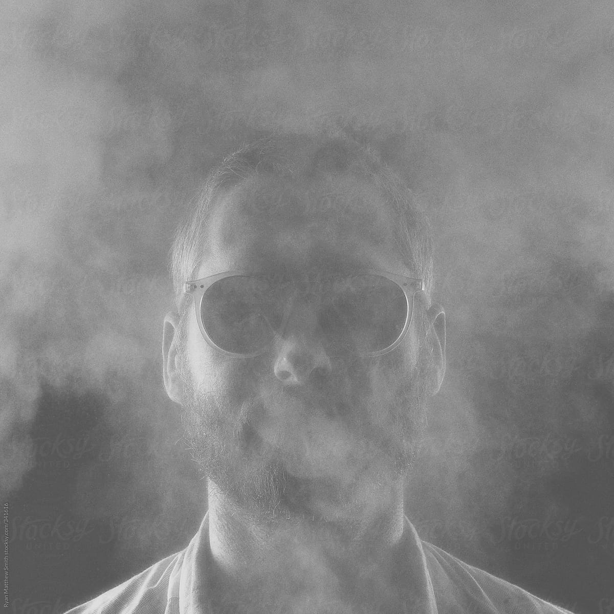 Young Man Hidden behind Smoke and Glasses