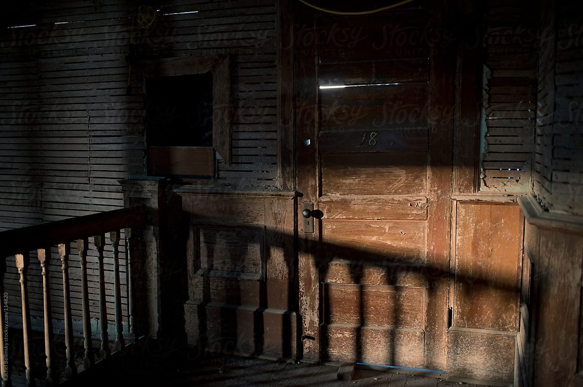 An old, splintered door in afternoon shadows at an abandoned school