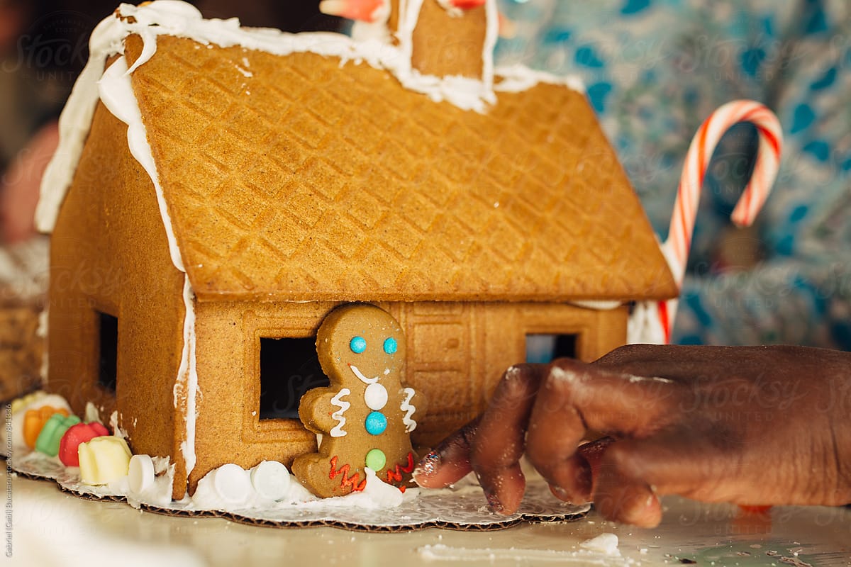 Black girl's hand working on a gingerbread house
