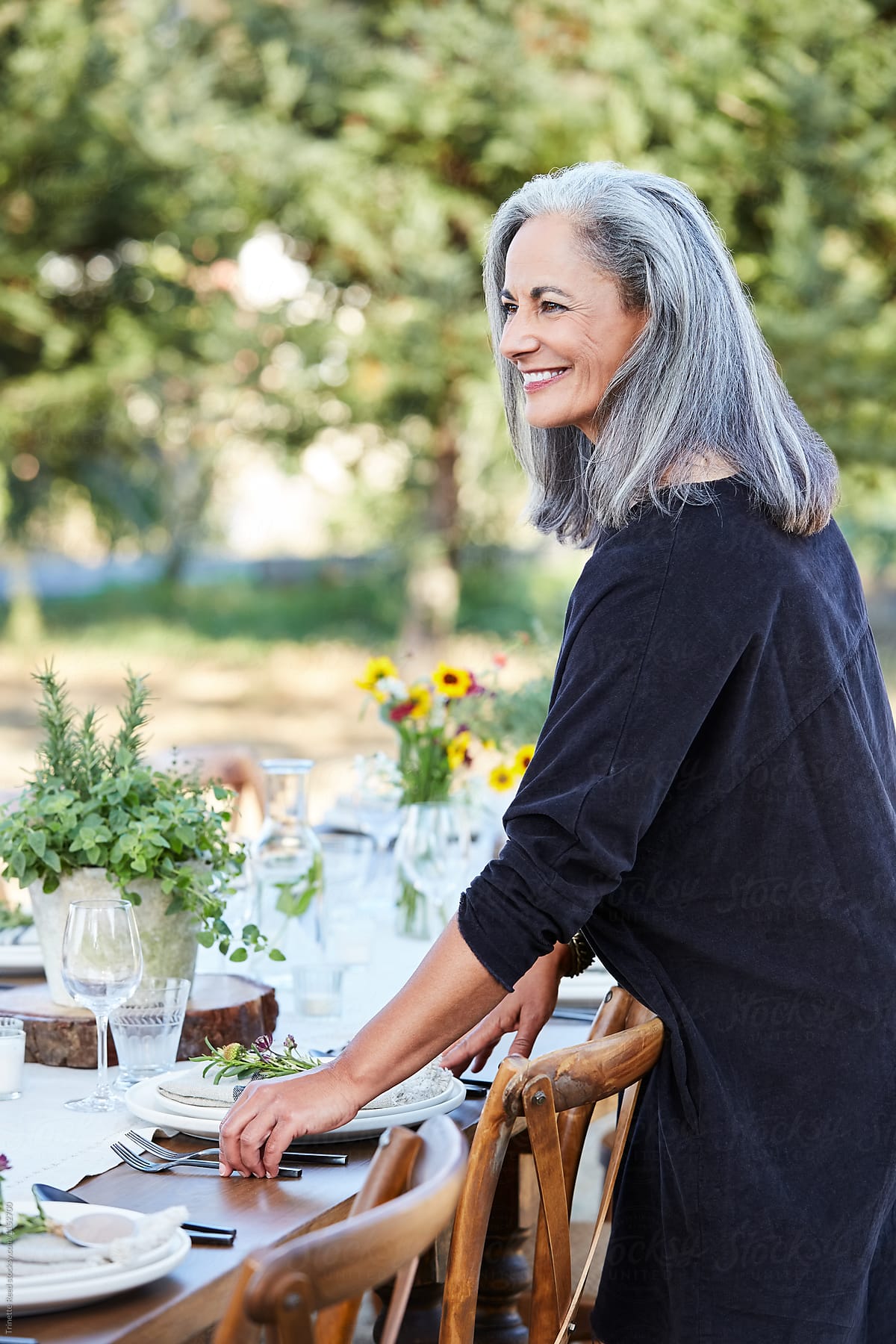 Beautiful senior woman setting the table for a farm to table dinner party