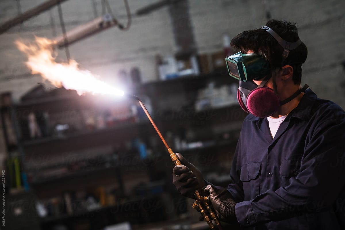 Welder adjusts his torch viewed from side