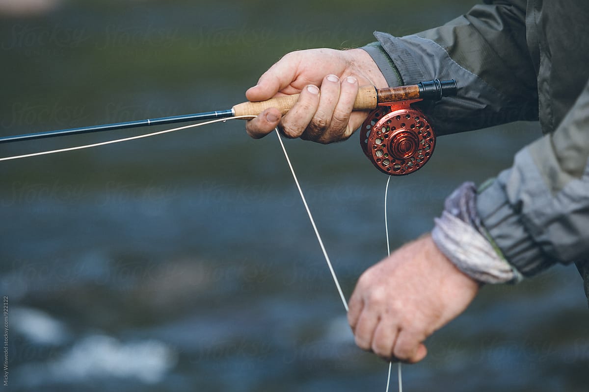 closeup od hands, reel and rod of a fly fisherman