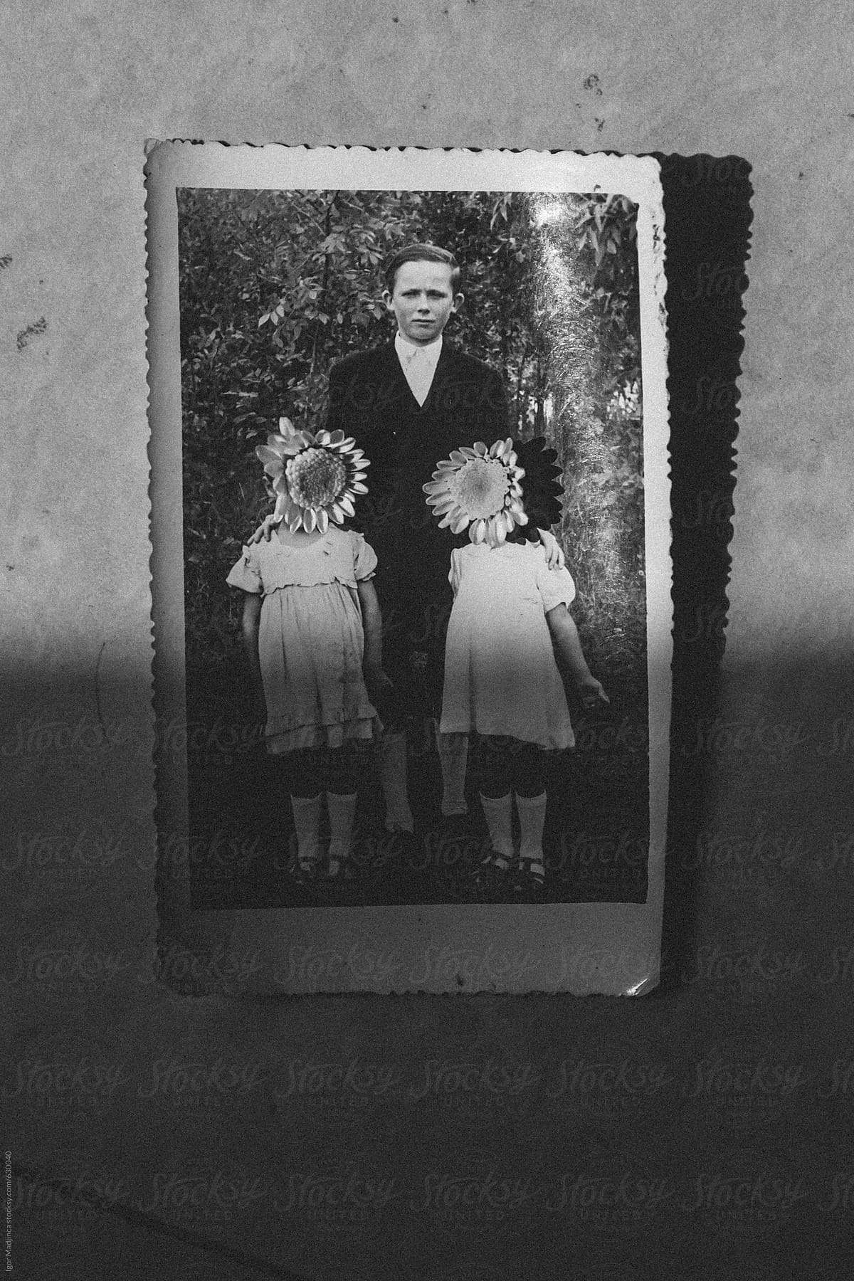 old photo in semi shade, family, children with flowers over their faces, hidden