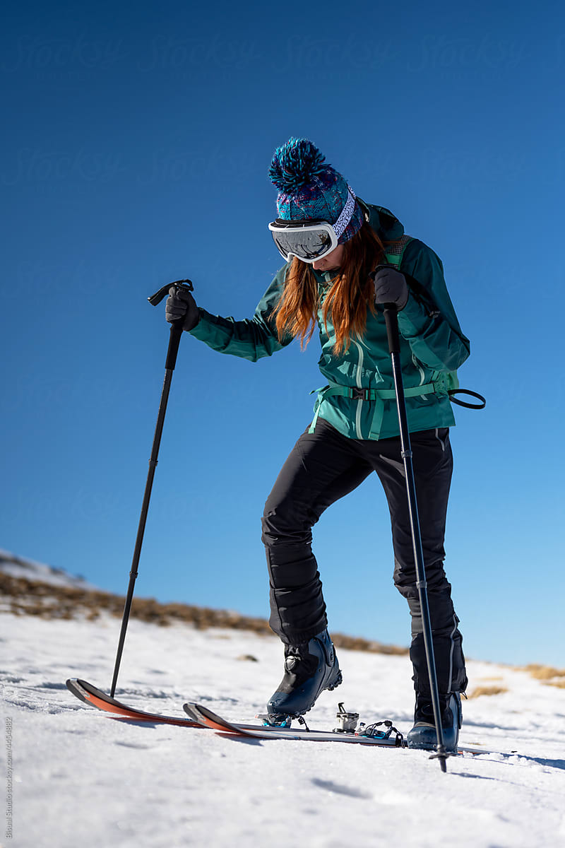 Mountaineer putting on skis in snowy highlands