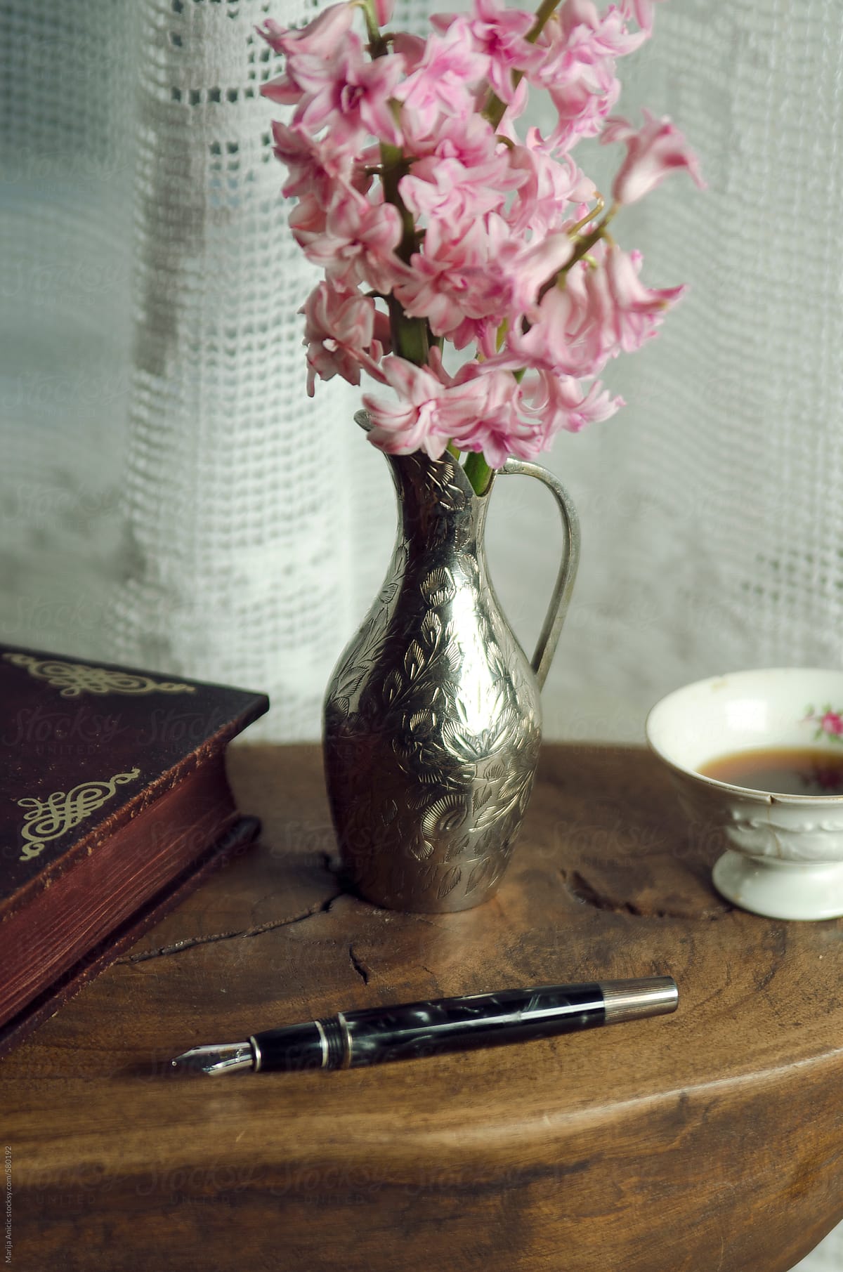 Silver vase with pink flowers,cup of coffee,notebook and pen