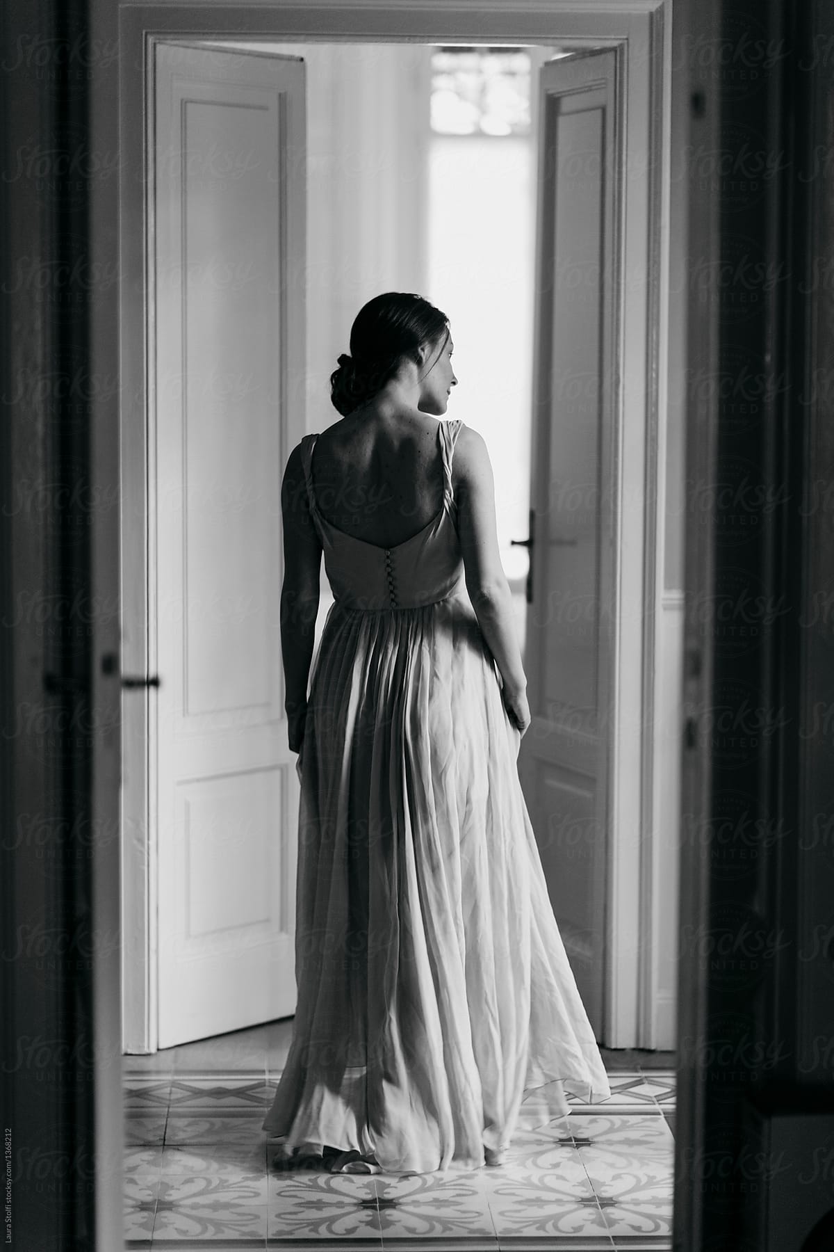 Rear black and white portrait of beautiful woman wearing a long party dress