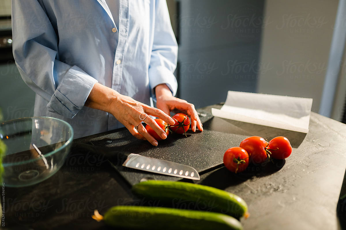 A woman is slicing tomatoes