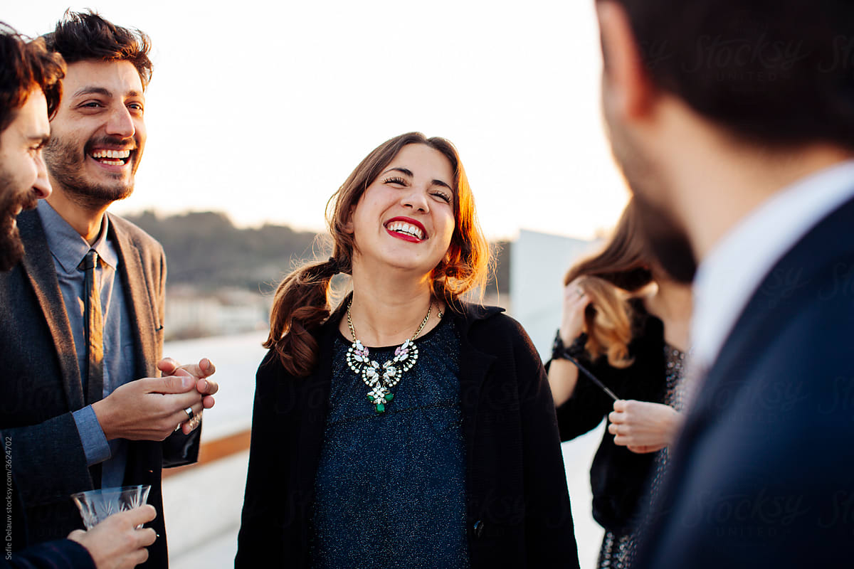 Crop happy colleagues talking during festive event on rooftop