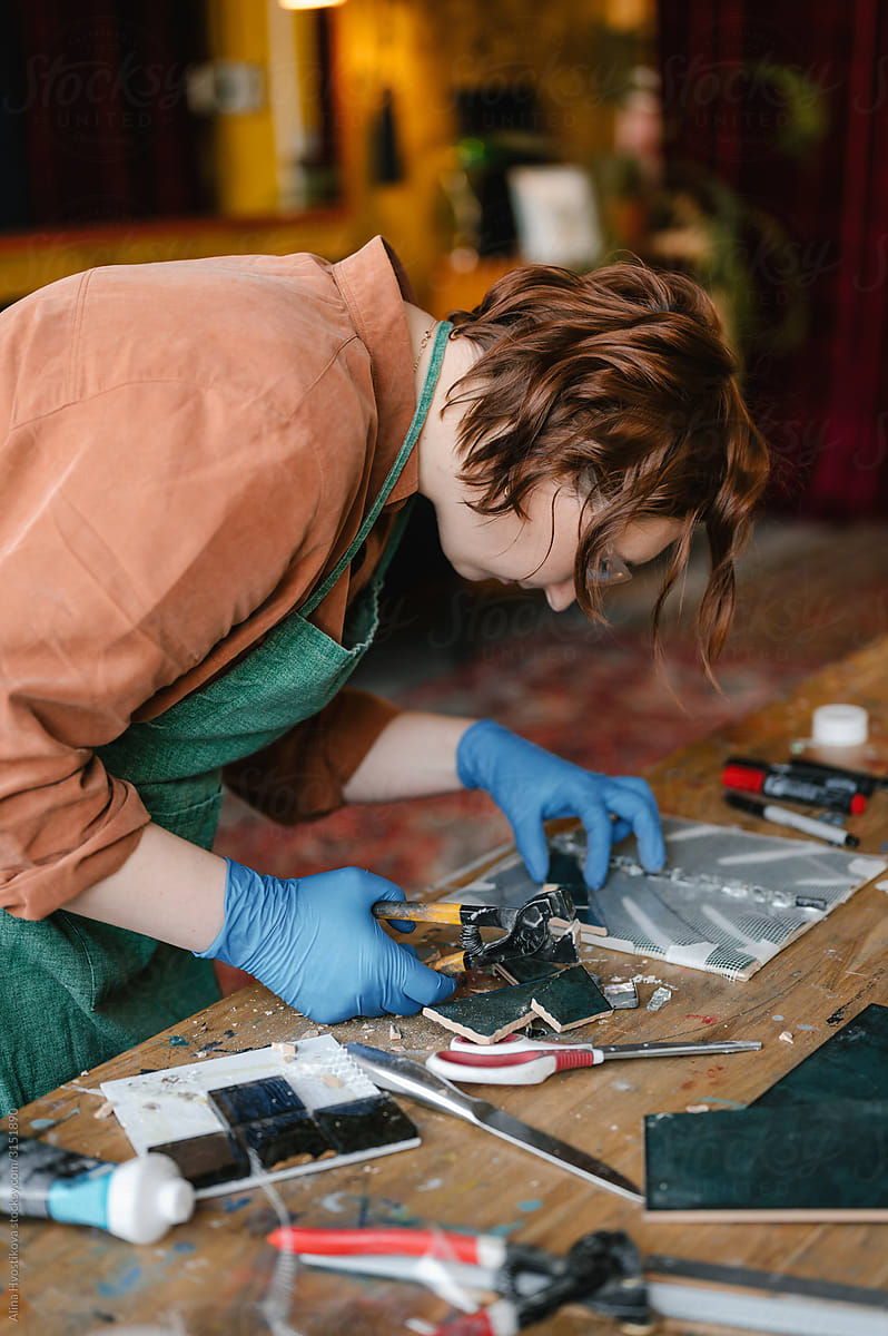 Craftswoman cutting and arranging mosaic pieces