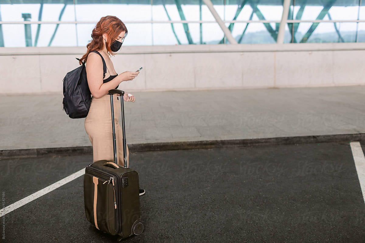 Woman with luggage looking the phone at airport