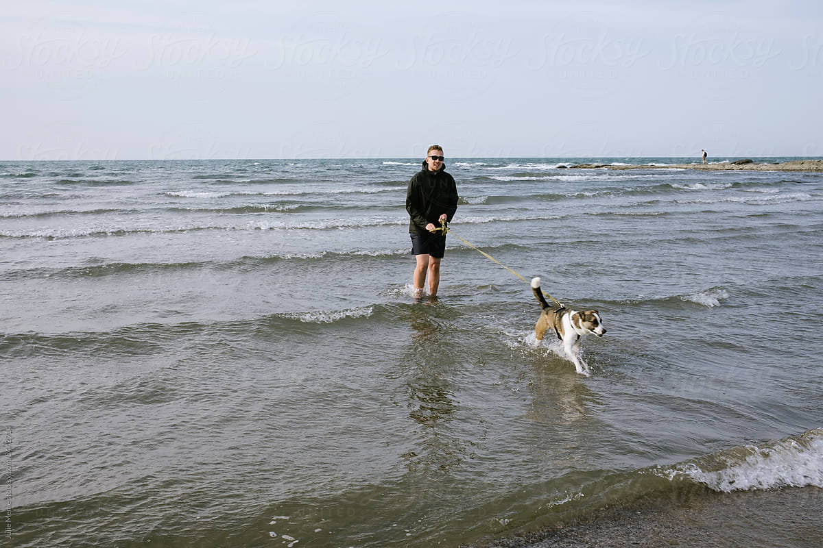 Man and Dog Playing in Sea Waves at Beach