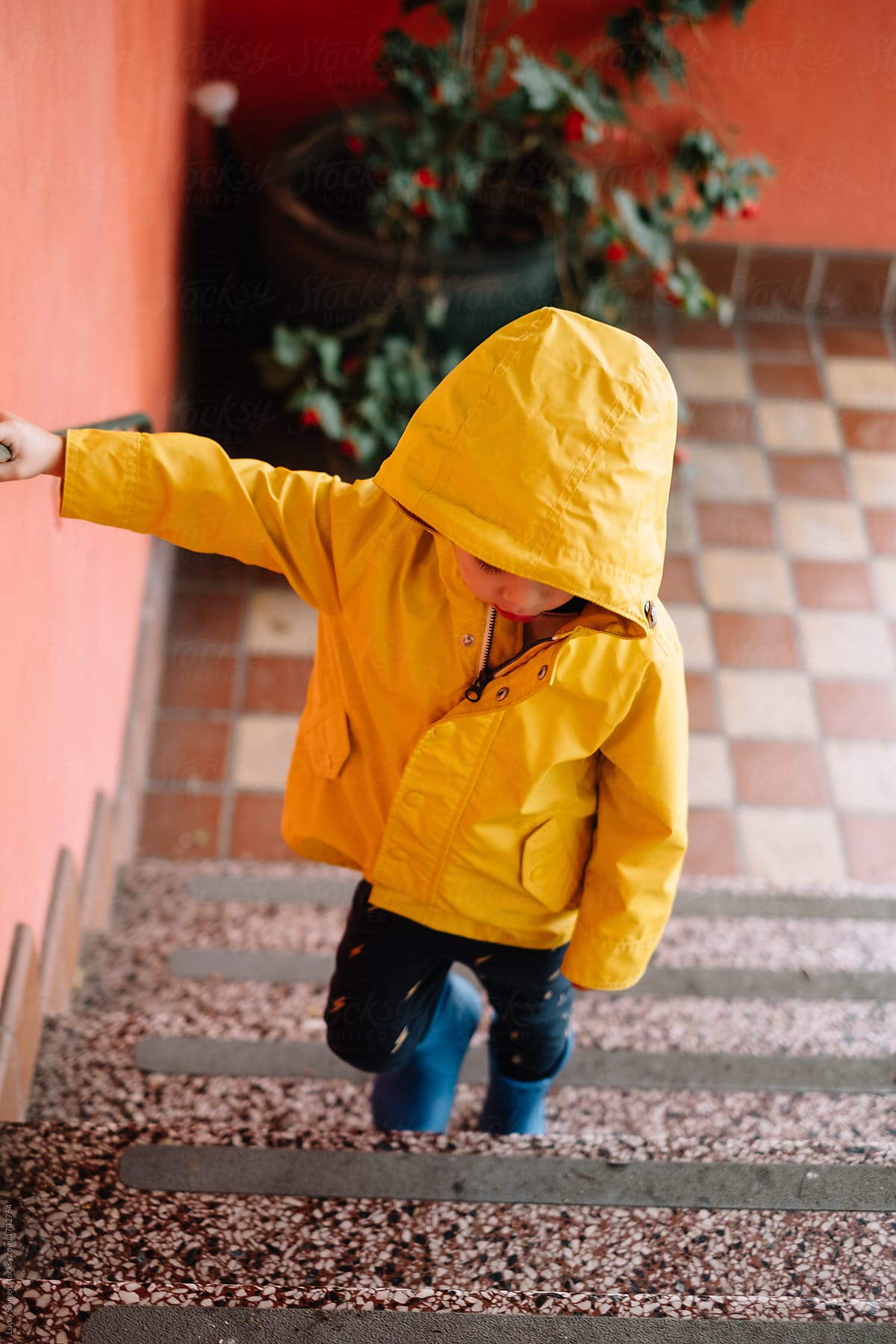 Boy in raincoat walking up stairs