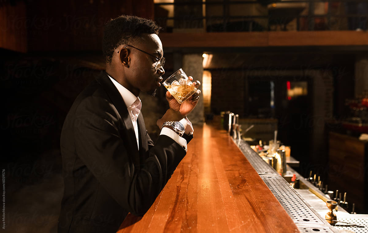 A wealthy man in a suit is relaxing in a bar after work