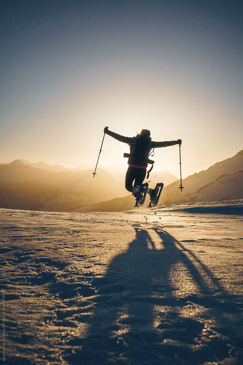 Cheerful woman jumping with snow shoes.
