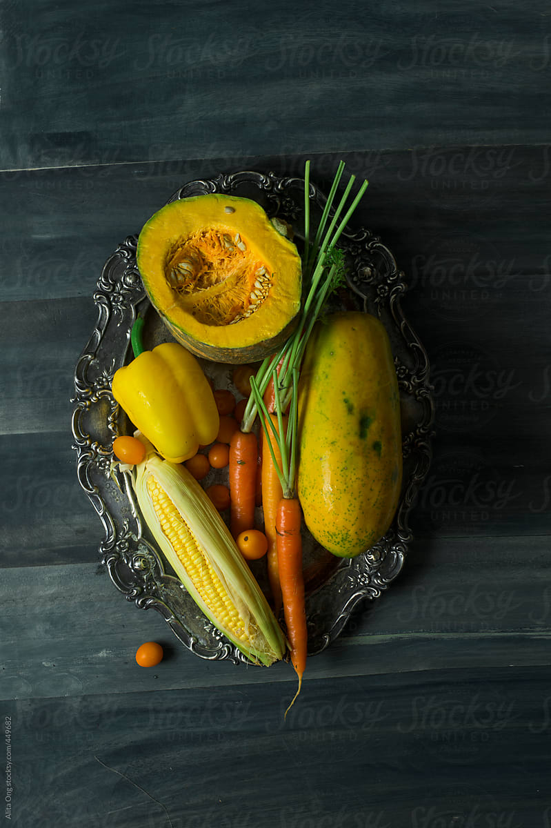 Yellow fruits and vegetables on rustic metal tray