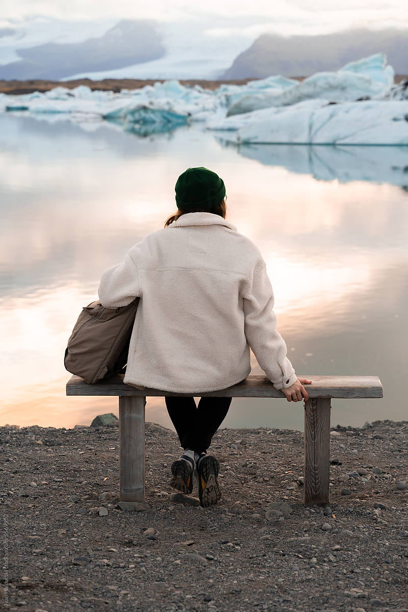 woman form behind on bench enjoying tranquil sunset at glacier lagoon