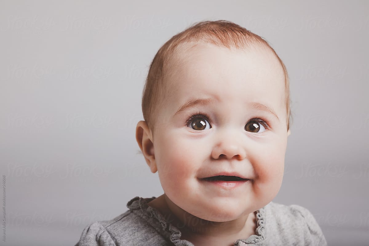 Cute baby girl smiling on solid background