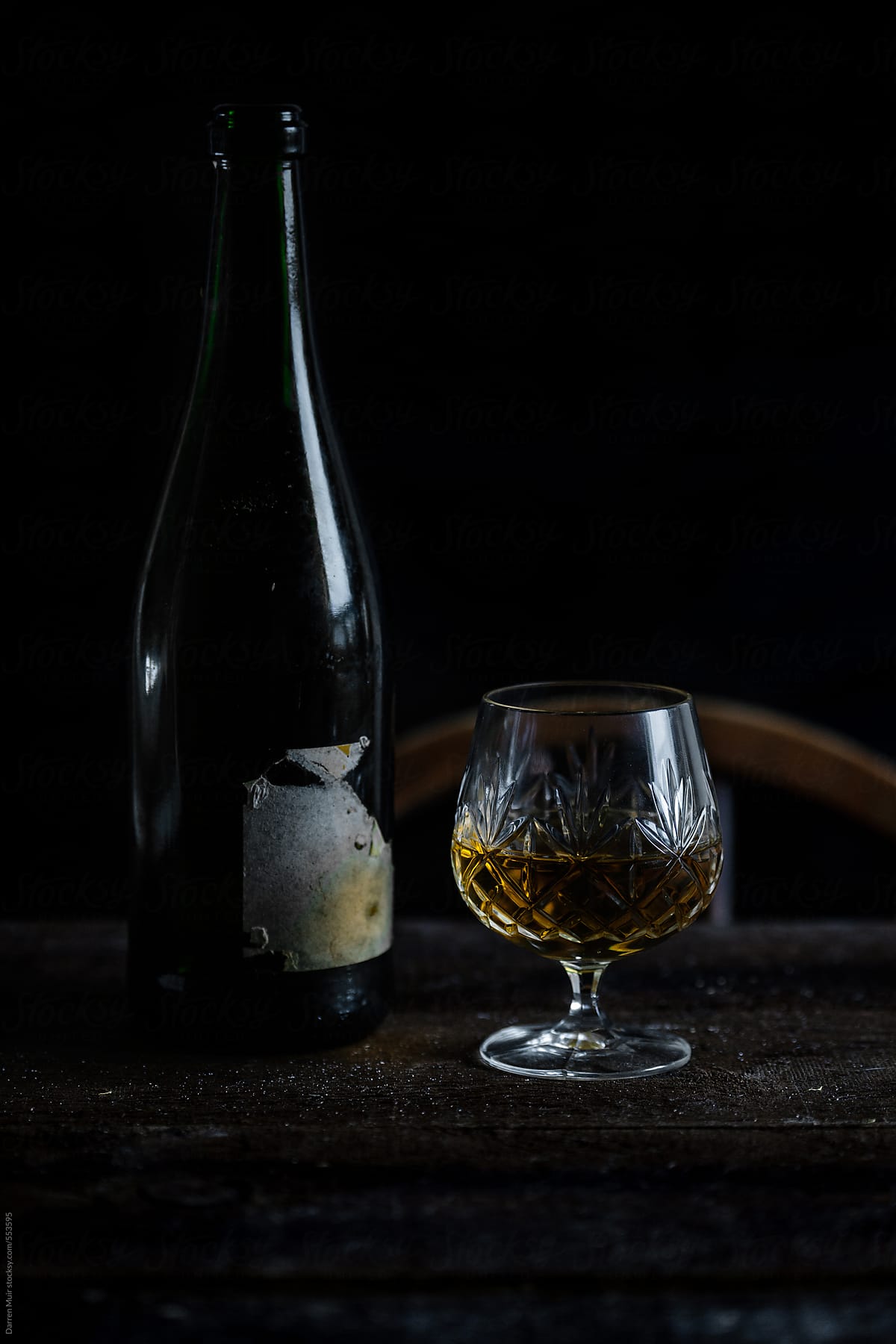 Vintage sherry bottle and crystal glass in natural low light setting.