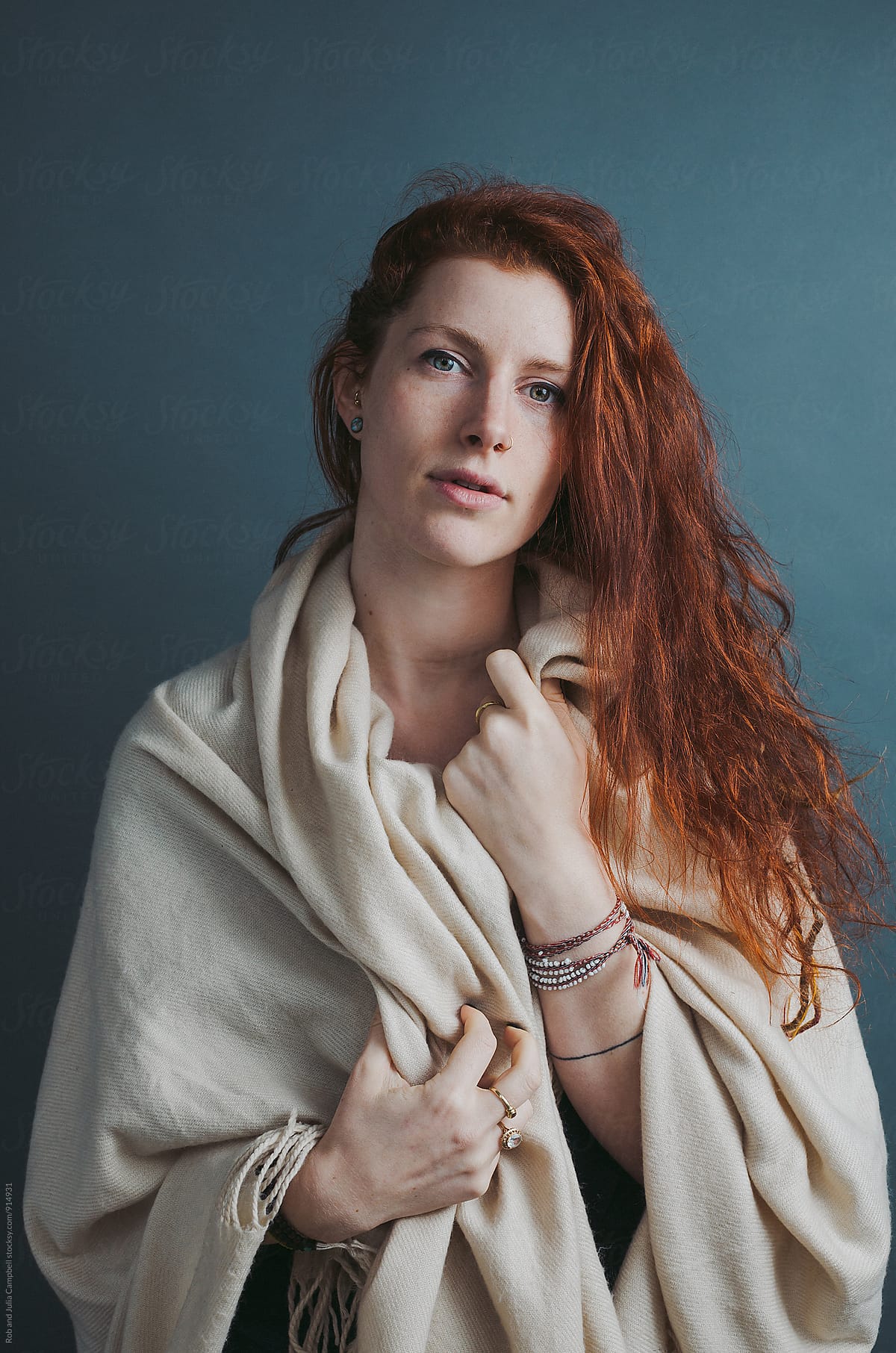 Portrait of young red head woman with blanket on solid background