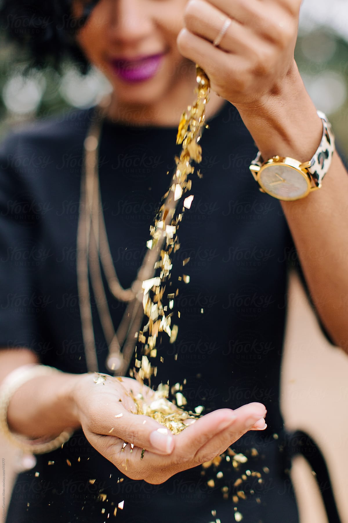 Woman pouring gold glitter / confetti in her hands.