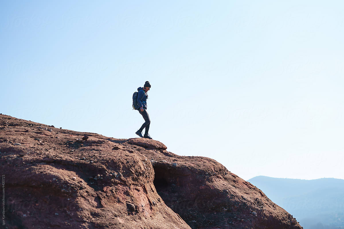 Brave hiking woman walking on huge cliff top