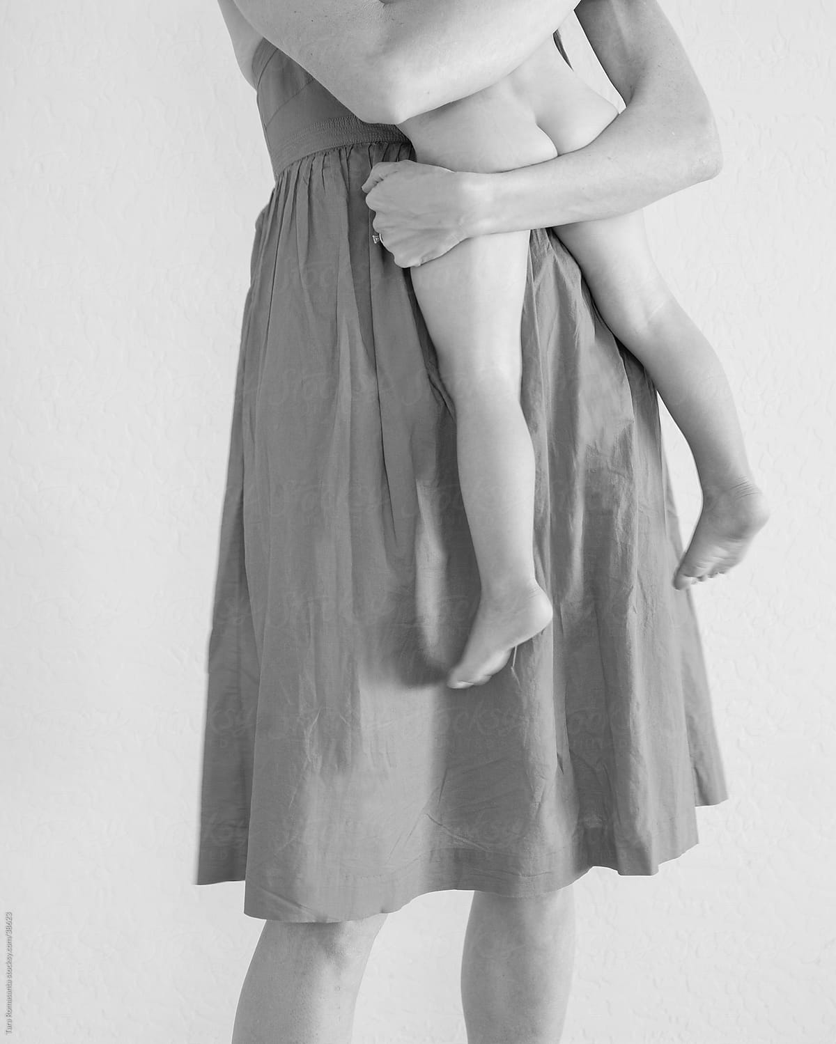 a mom holds a bare bottomed toddler in her arms