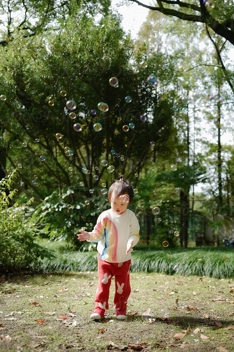 Asian baby chasing bubbles in the park