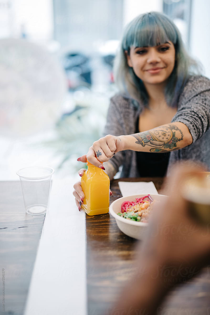 Woman having juice and poke bowl in cafe