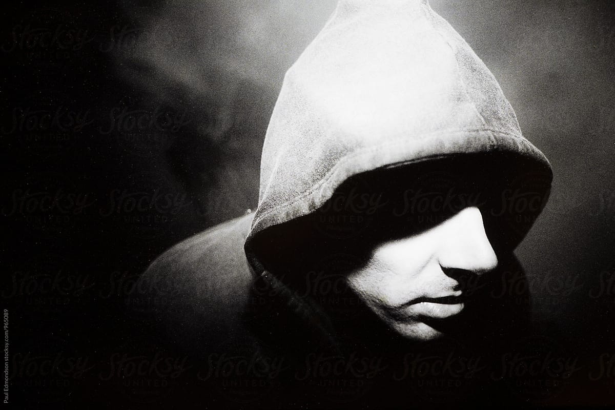 Portrait of man wearing hoodie in dark alley, shadow ...