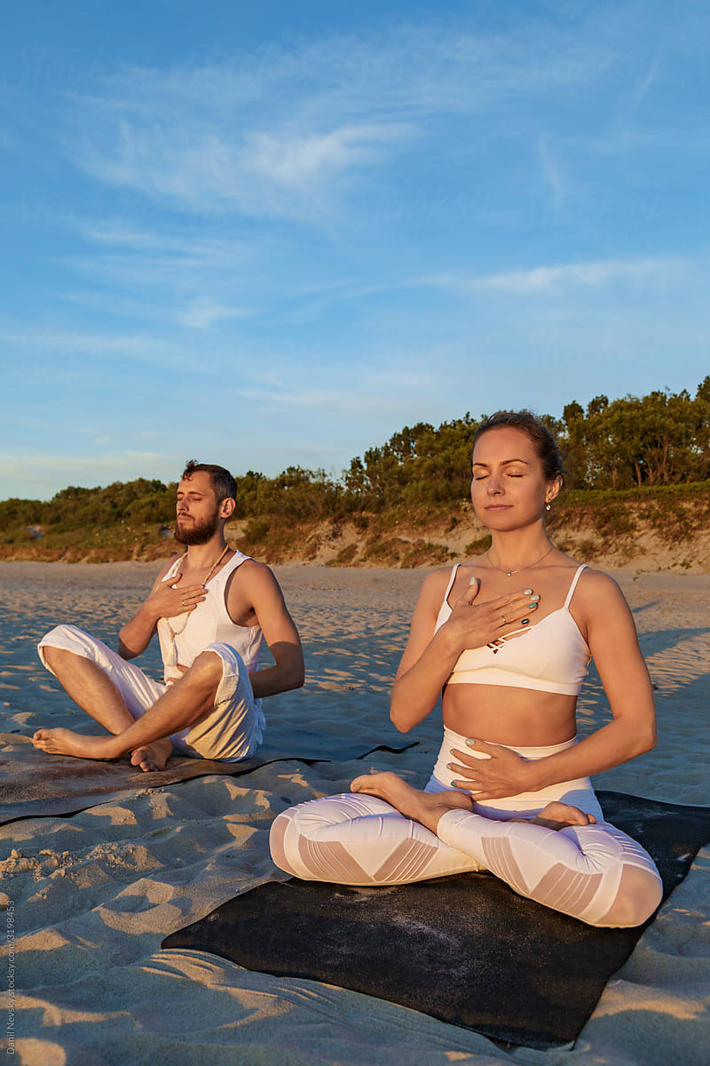 Couple doing respiratory exercise during meditation on beach