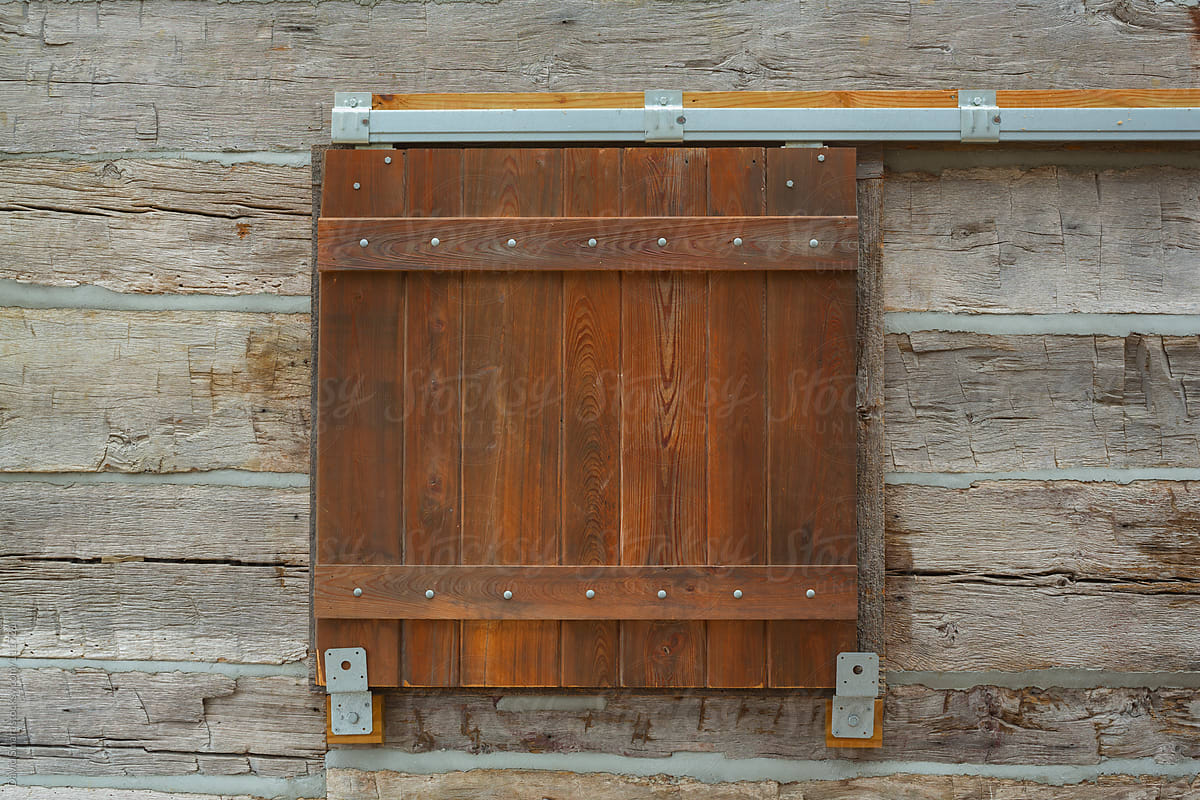 Barn door style window shutter on a log cabin