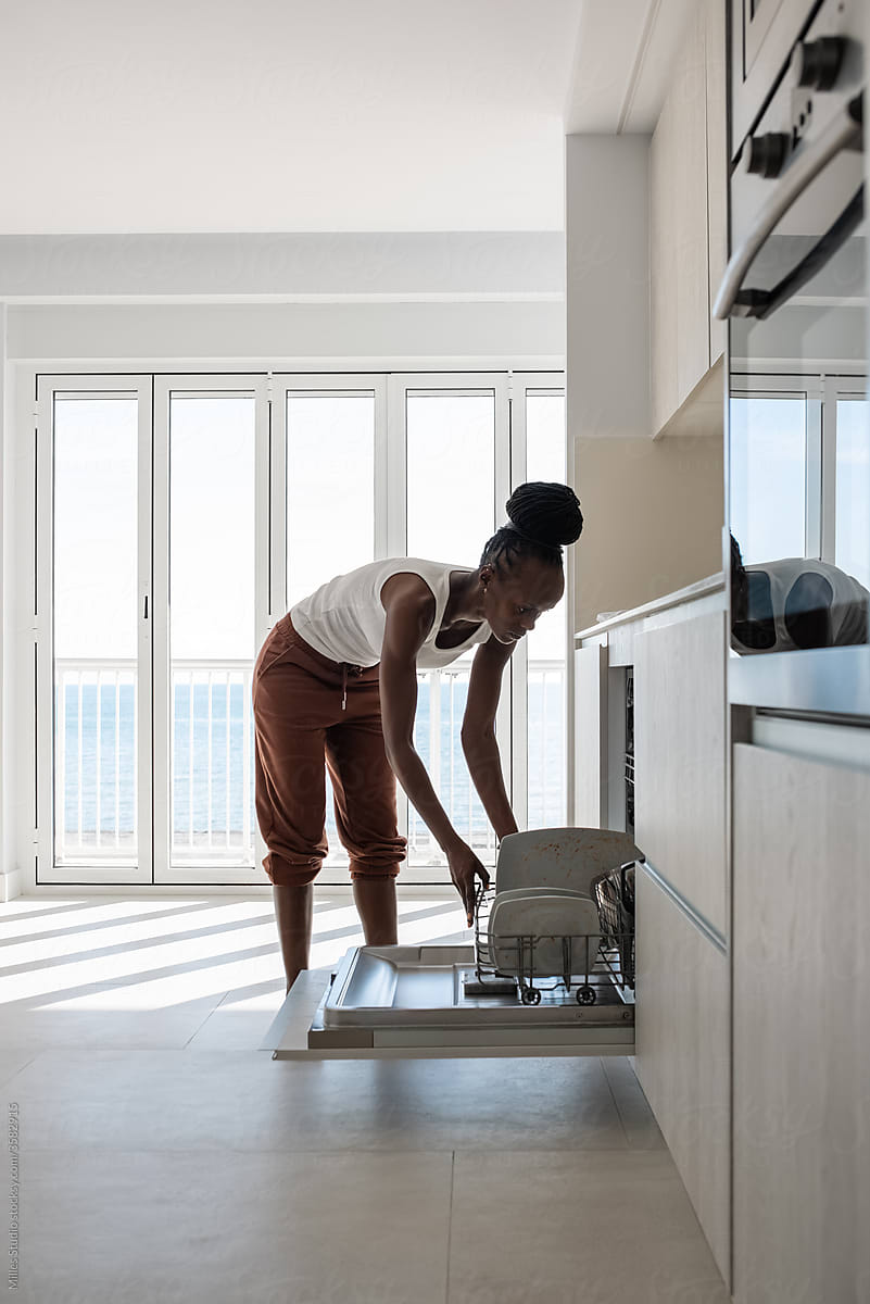 Black woman loading plates into dishwasher