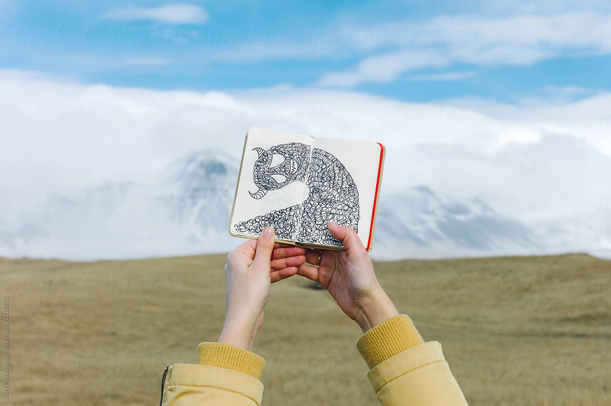 Crop hands holding picture book on mountainscape