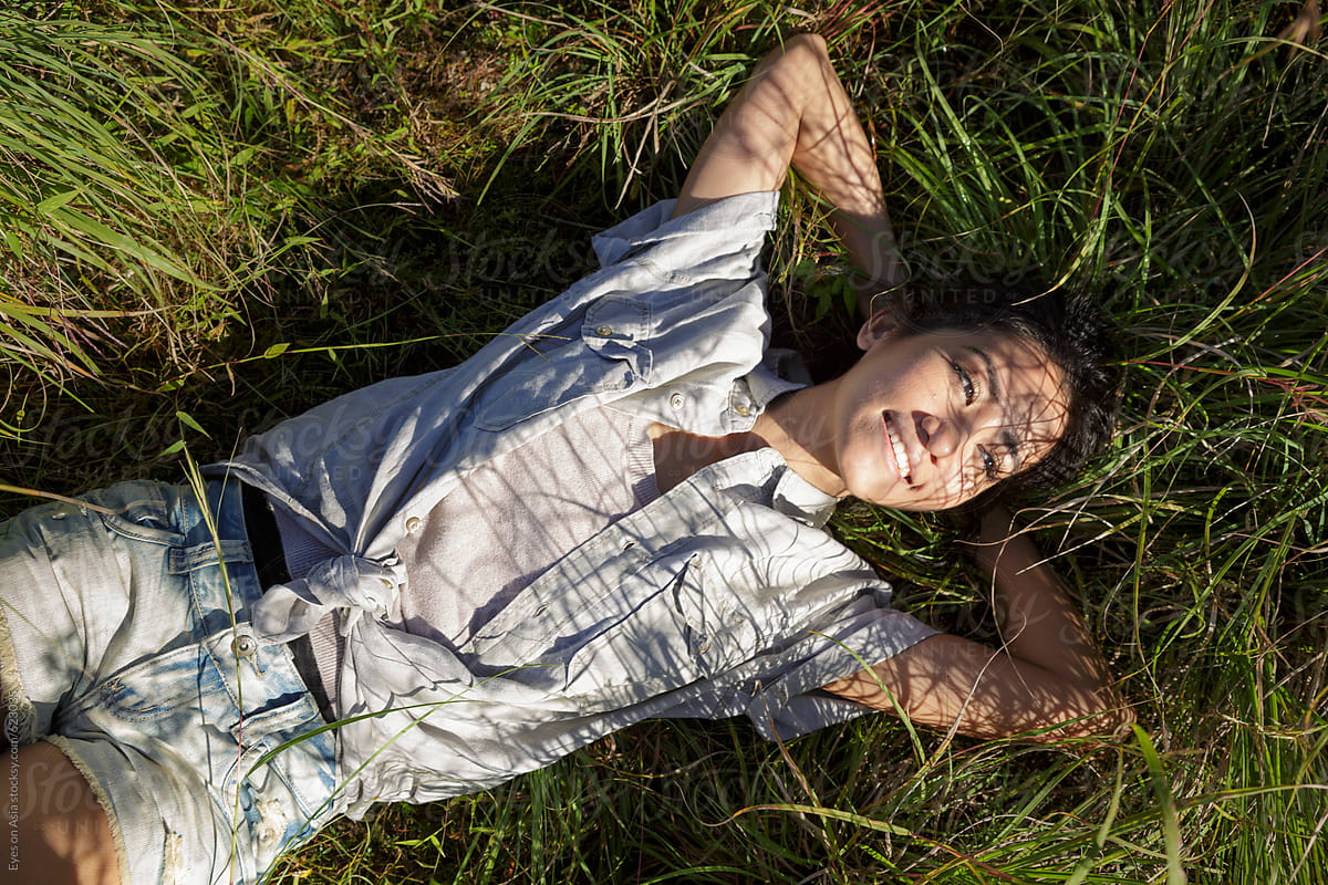 A young asian woman is lying in the gras