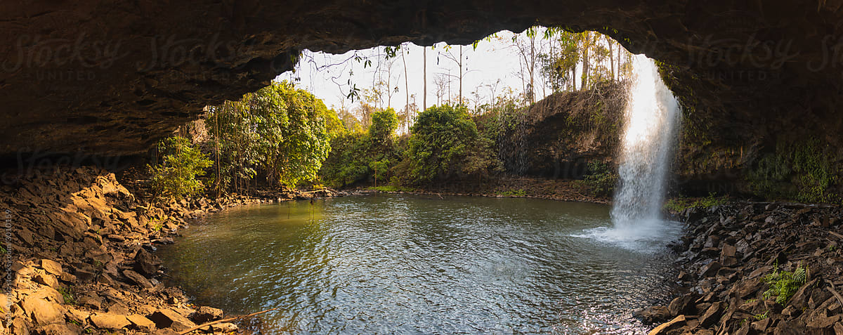 photo of waterfall over a cave and lake