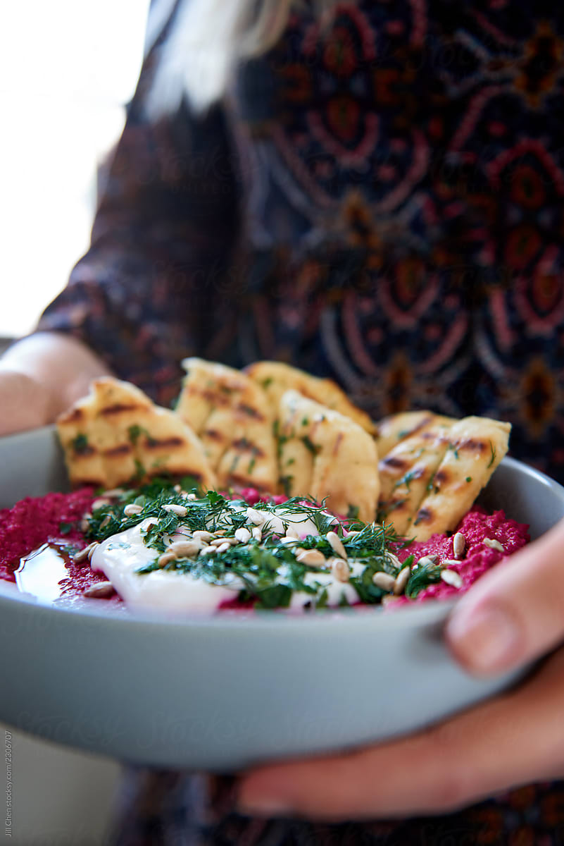 Party hostess taking out starter hummus dip with flat bread