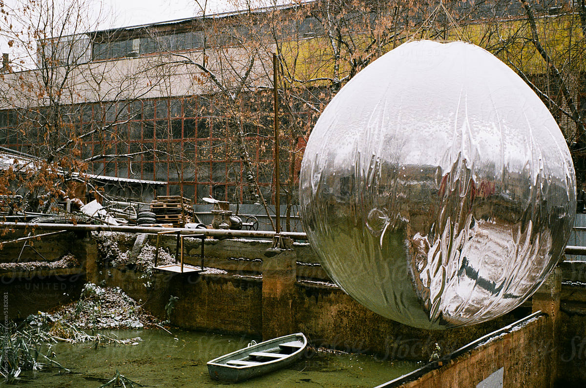 A huge tinfoil snow globe hangs over a pool of green water