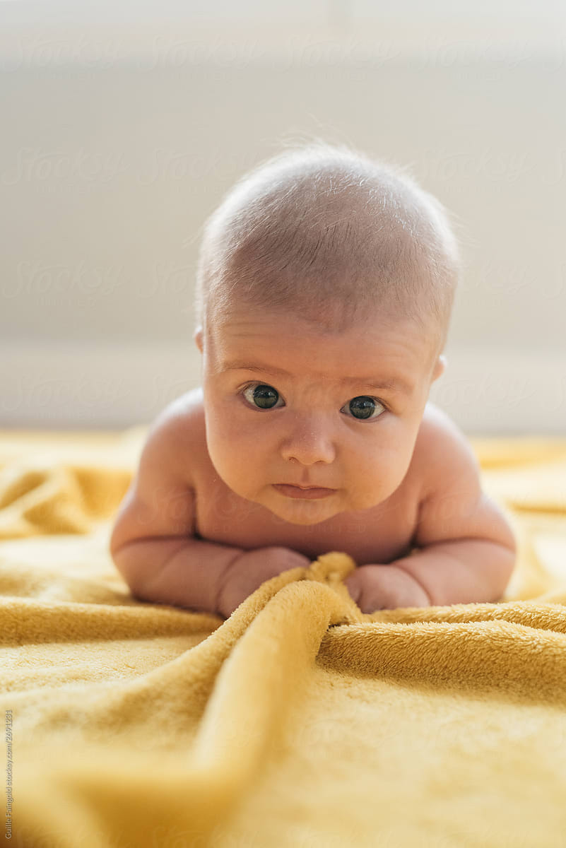 Adorable baby on yellow blanket looking at camera