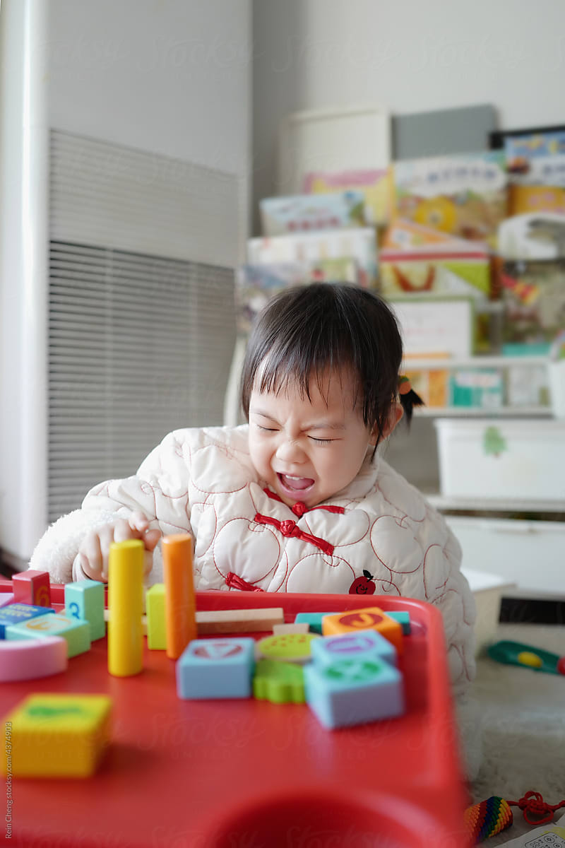 Asian babygirl builds blocks alone