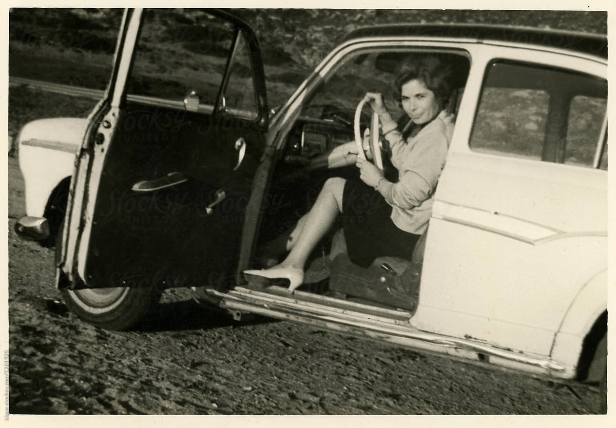 1960's Black and white photo of a woman sitting in the drivers seat of a car by kkgas for Stocksy United