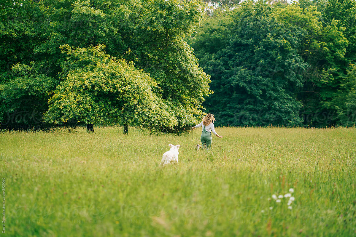 A blonde woman plays with her dog in a park