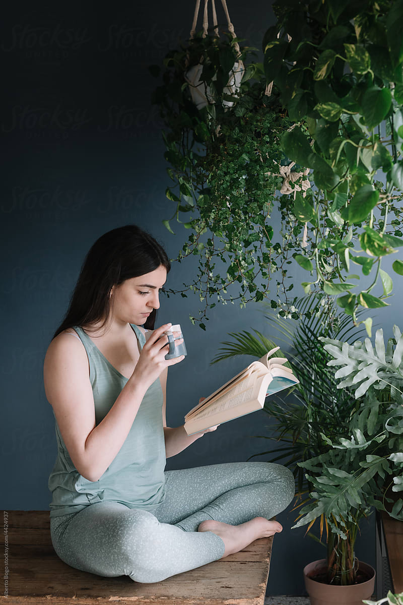 Young Woman Drinking Herb Tea In Studio On Wooden Table