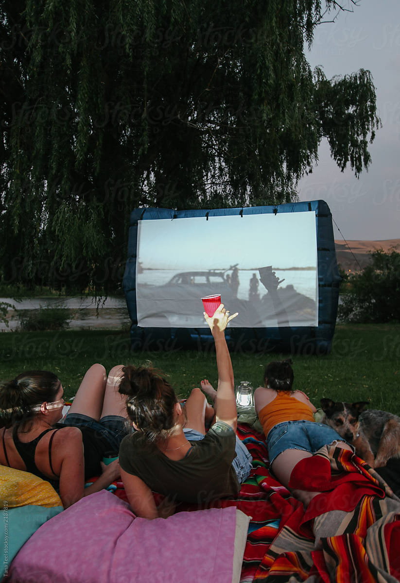 friends and family enjoy watching outdoor movie in yard