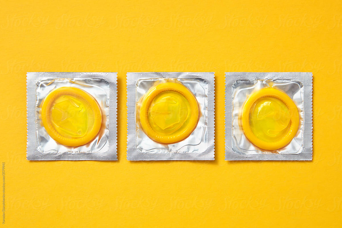 Three yellow condoms on an yellow.