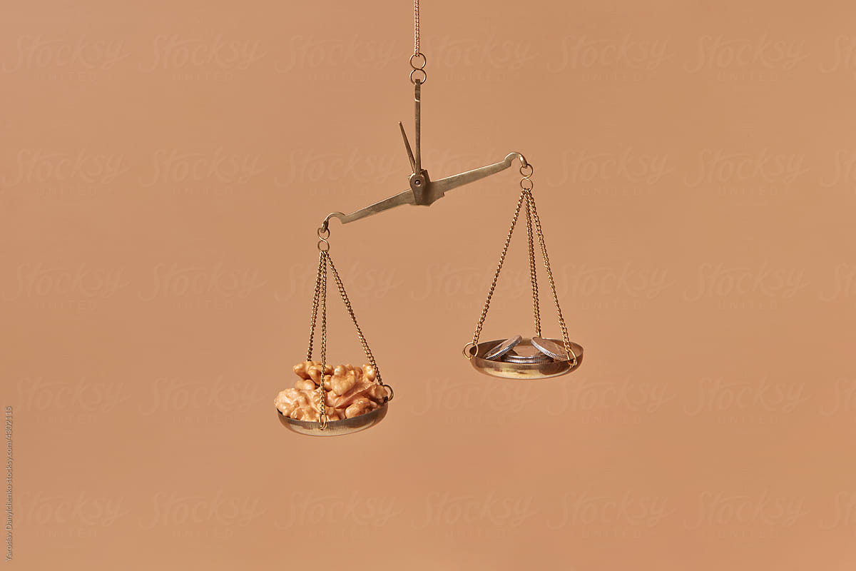 Golden scales with pile of coins and walnuts