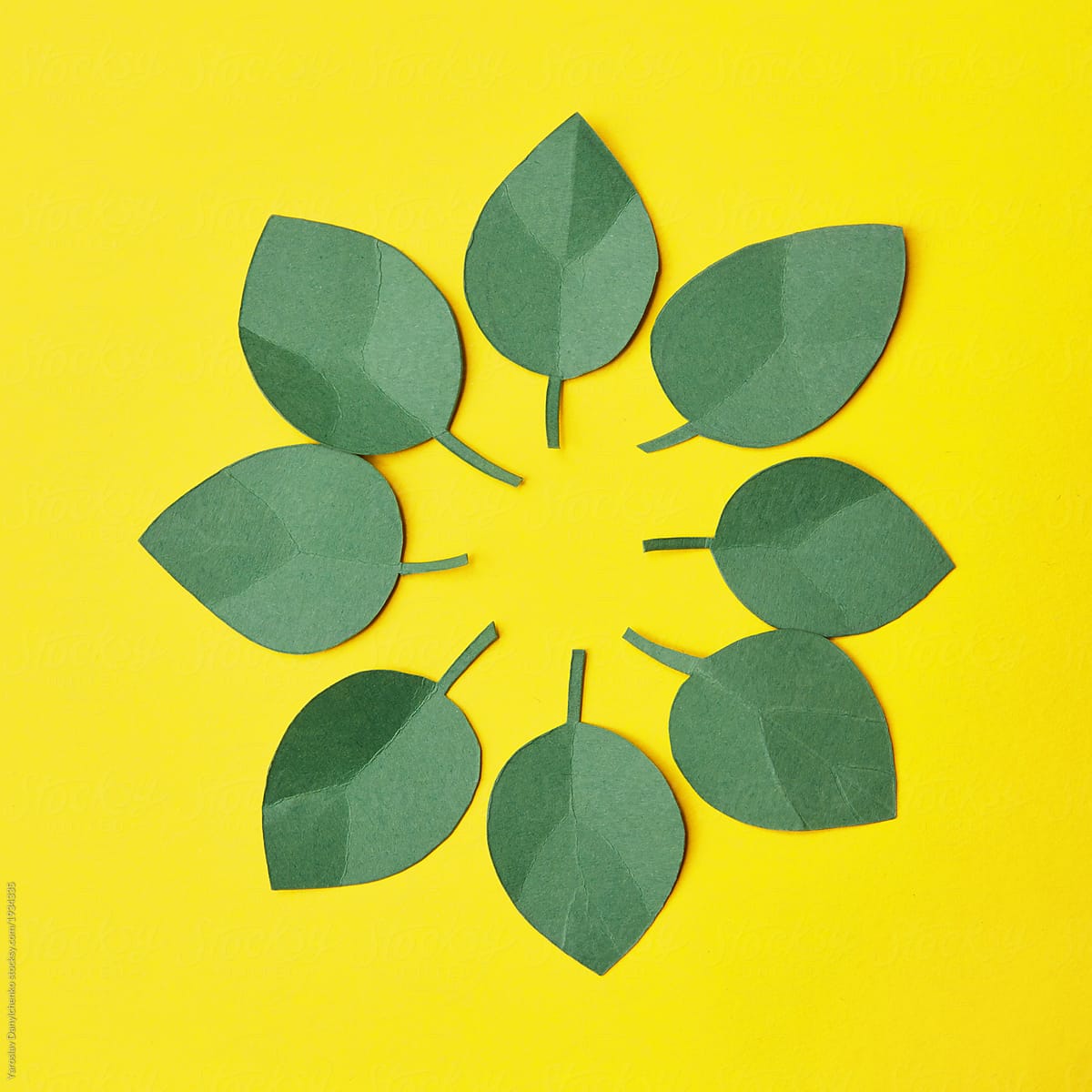 Paper craft green leaves in round shape on a yellow background,