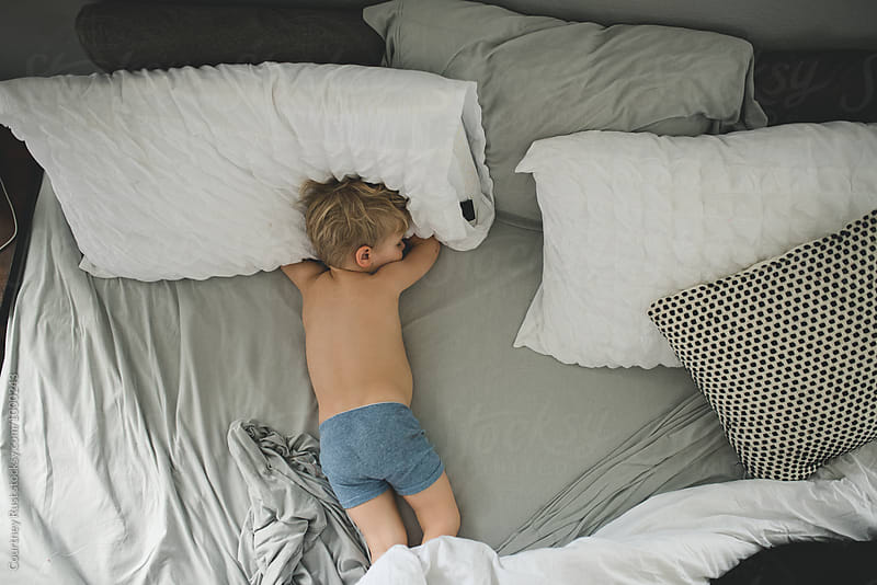 Boy napping in parent\'s bed in boxer briefs