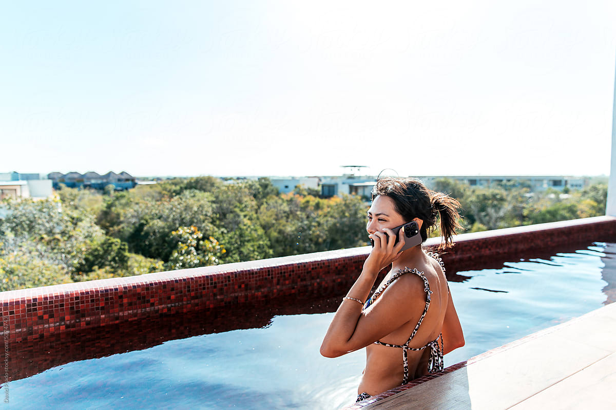 Woman in bikini talking on smartphone in water