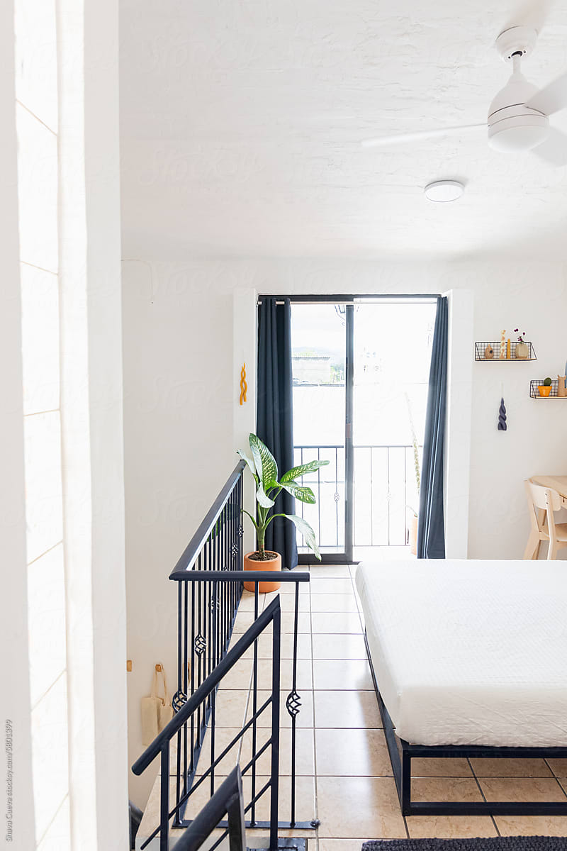 A room with a bed with white sheets next to a balcony