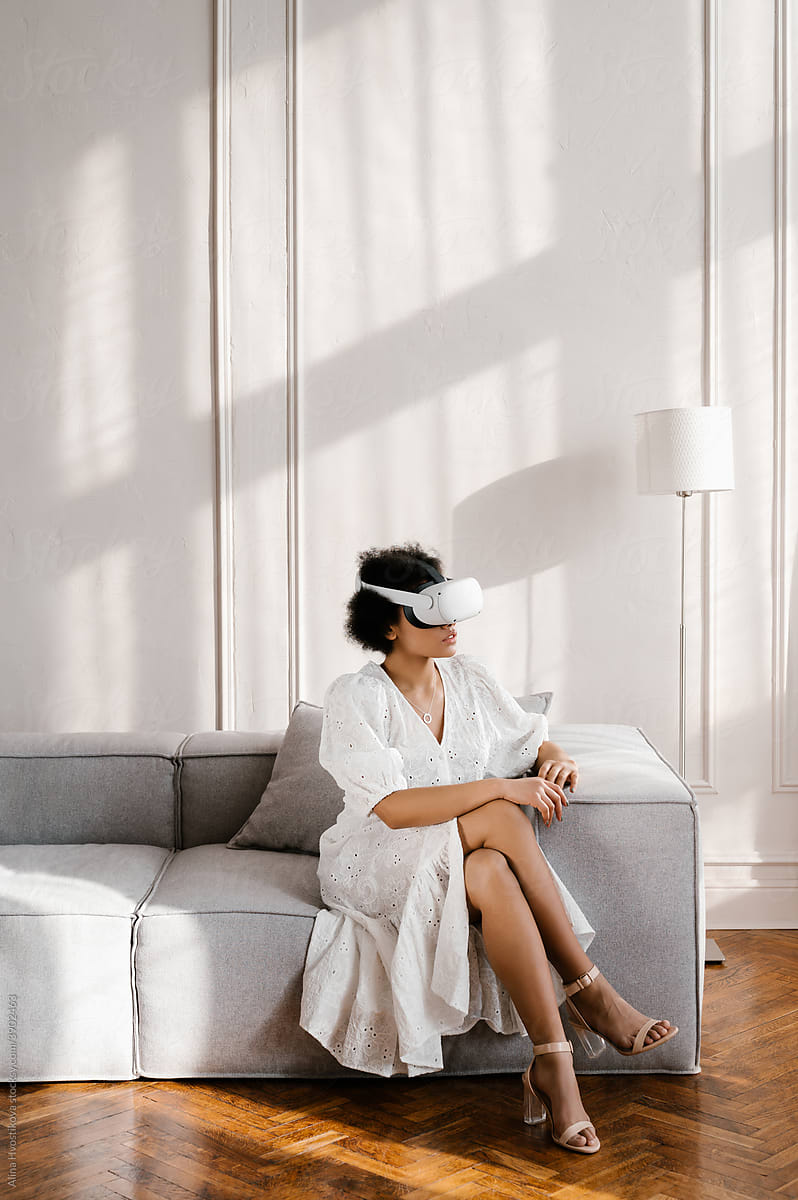 Black woman in VR glasses sitting on sofa